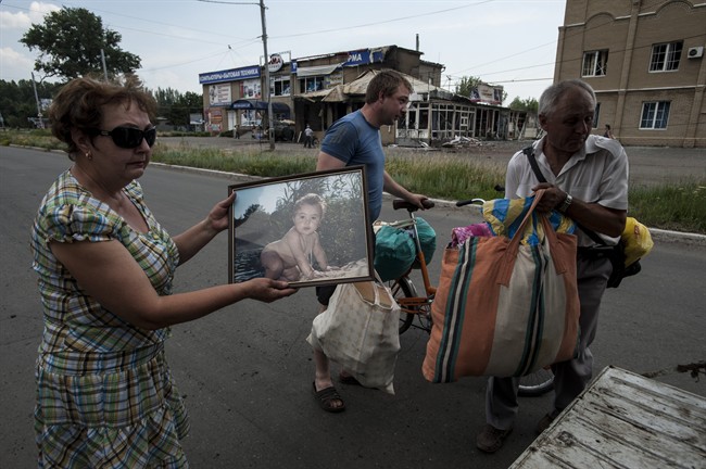 A woman shows a photo of her grandson, as she and her relatives carry their belongings, leaving Slovyansk, eastern Ukraine, Monday, June 9, 2014 after a mortar attack by Ukrainian government forces. 