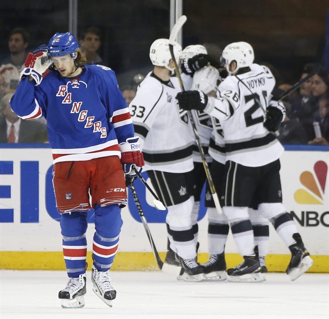 New York Rangers Carl Hagelin (62), left, reacts as the Los Angeles Kings Willie Mitchell (33) and Slava Voynov (26), celebrate a second period goal by Mike Richards, center, during Game 3 of the NHL hockey Stanley Cup Final, Monday, June 9, 2014, in New York.