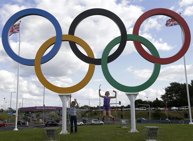 FILE - In this July 28, 2012 file photo, British children pose for photos under a sculpture of the Olympics rings, in Coventry, England. Boston, Los Angeles, San Francisco and Washington are the cities still in the running for a possible U.S. bid to host the 2024 Summer Olympics.