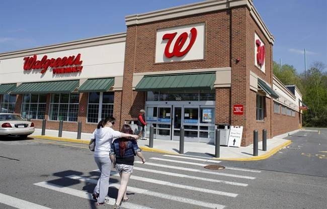 In this Wednesday, May 14, 2014 photo, customers walk toward an entrance to a Walgreens store location, in Boston. 