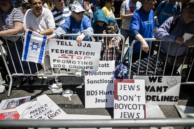 In this Sunday, June 1, 2014 file photo, protesters against the Boycott, Divestment and Sanctions (BDS) movement stand behind a police barricade during the Celebrate Israel Parade in New York.
