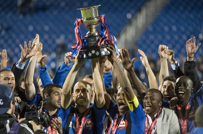 Montreal Impact Marco Di Vaio, left, and Patrice Bernier are surrounded by teammates after winning the Voyageurs Cup