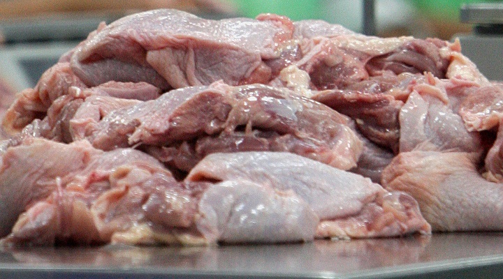 Pieces of raw chicken sit on a weighing machine.