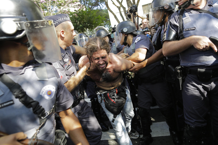 A protester is detained by police during a demonstration by people demanding better public services and against the money spent on the World Cup soccer tournament in Sao Paulo, Brazil, Thursday, June 12, 2014.