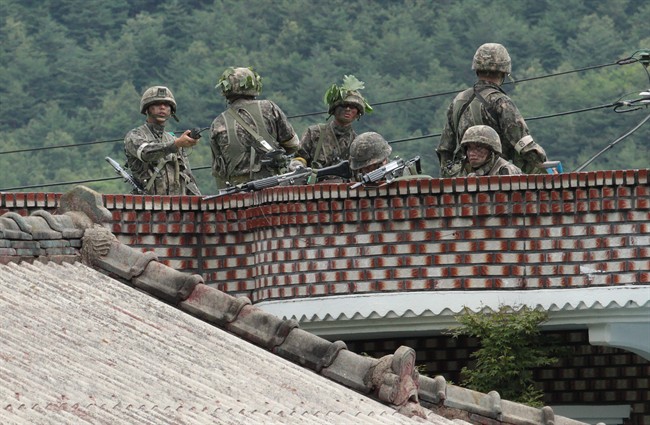 South Korean army soldiers take position on the roof of a private house to search for a South Korean conscript soldier who is on the run after a shooting incident in Goseong, South Korea, Sunday, June 22, 2014. The military searched Sunday for an armed South Korean soldier who fled after killing five of his comrades and wounding seven at an outpost near the North Korean border. (AP Photo/Ahn Young-joon).
