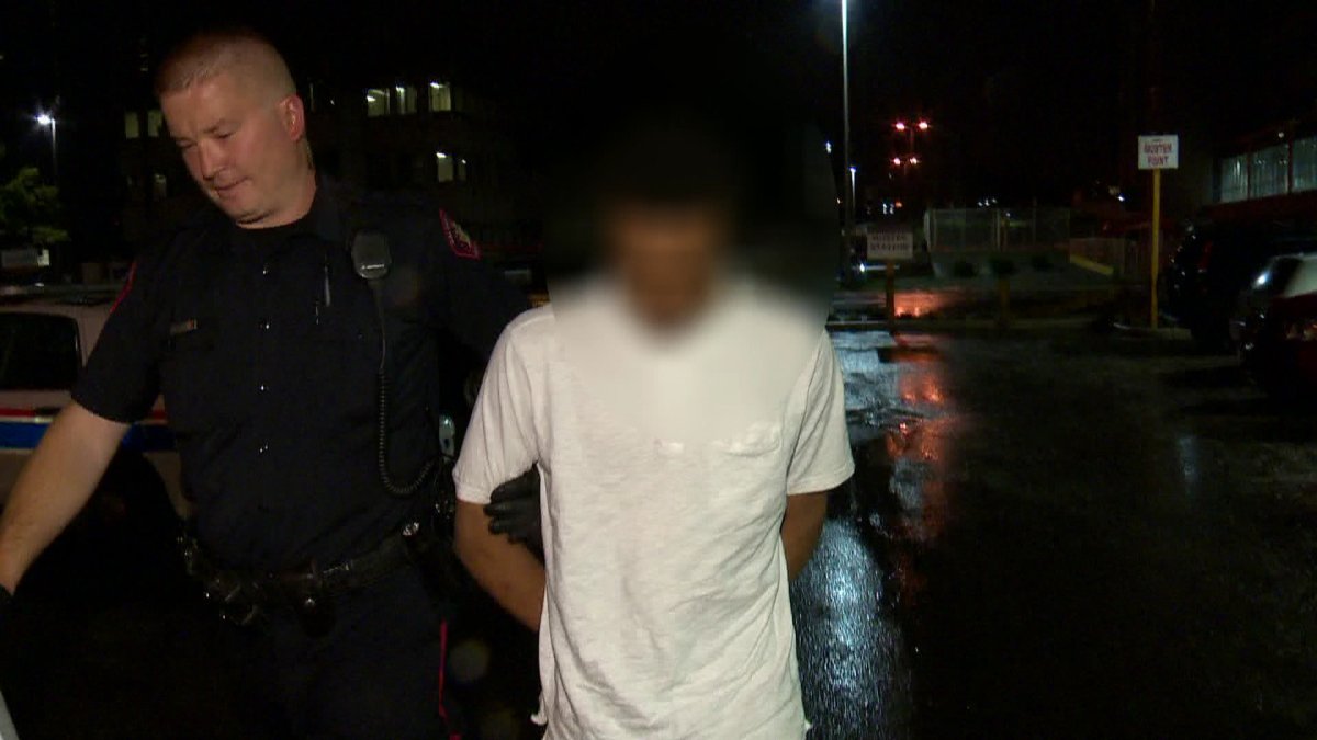 Calgary police take a suspect into the arrest processing on Wednesday, June 18th. His face is blurred because it's believed he is a minor.