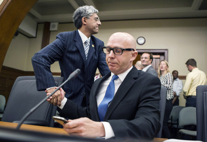 Don Guy, right, shakes hands with chair Shafiq Qaadri as he checks messages on his phone after attending the Justice Committee hearing in Toronto on Tuesday, August 13, 2013.