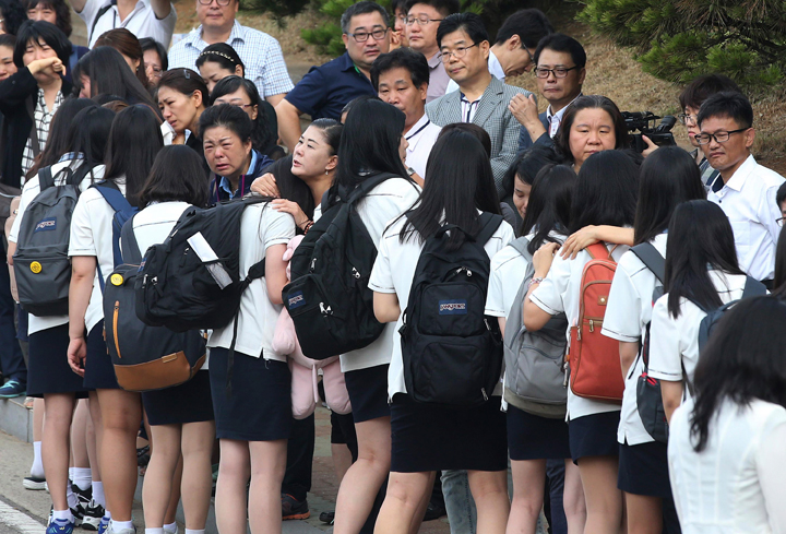 Students who survived the sinking of a ferry Sewol are comforted by parents of their friends who lost their lives in the disaster as they make their way back for their first class since the disaster in Ansan, South Korea, Wednesday, June 25, 2014. 