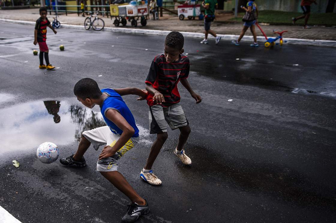 Brazilian children play football on a street near the Fonte Nova Arena stadium in Salvador on June 8, 2014, ahead of the 2014 FIFA World Cup in Brazil. AFP PHOTO / DIMITAR DILKOFF (Photo credit should read DIMITAR DILKOFF/AFP/Getty Images)