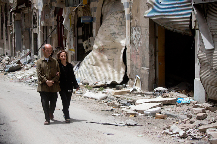 In this Thursday, June 5, 2014 photo, Zeinat Akhras and her brother Ayman walk to from home to a church in Homs, Syria. Over the course of the 700-day blockade, Zeinat’s world shrunk to her living room and her kitchen. She survived reading books, eating plants and refusing to look in the mirror, because seeing her withered state might break her spirit.