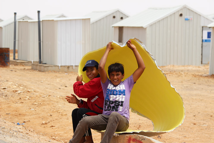 Boys take shelter from the sun under a reflective tarp