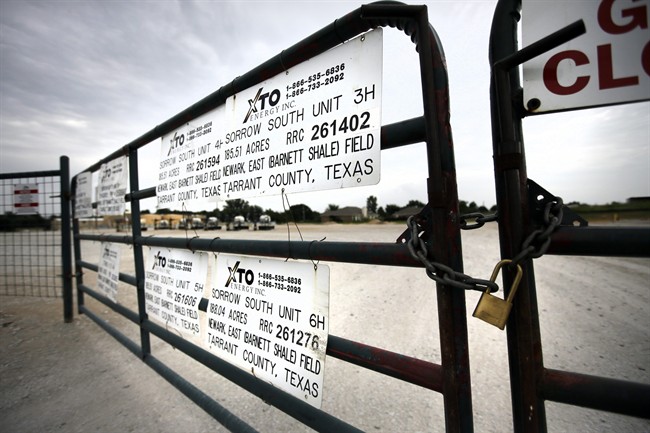 Signs on a locked gate show the number of operating wells at an XTO Energy Inc site, Saturday, June 21, 2014, in Azle, Texas. 