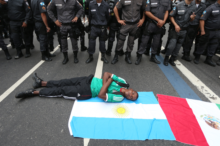 A protestor lies on flags in front of police during an anti-World Cup demonstration in the Copacabana section on June 12, 2014 in Rio de Janeiro, Brazil.