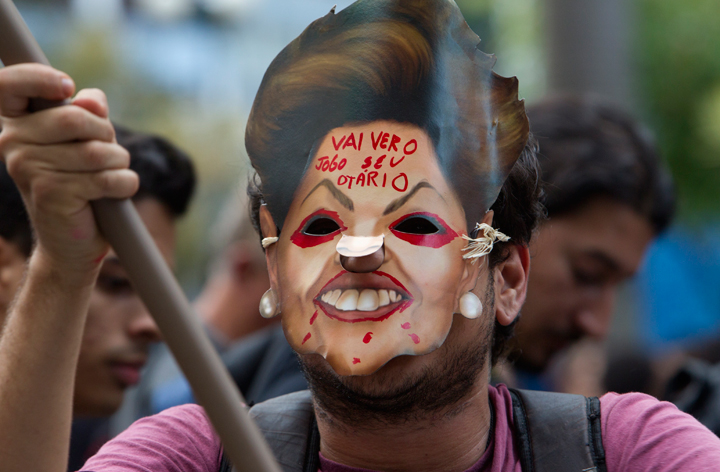 A demonstrator protest while wearing a mask with the face of Brazil’s President Dilma Rousseff and that reads in Portuguese, “Go to see the game, You fool”, during a march against the FIFA 2014 soccer World Cup, at Copacabana beach, Rio de Janeiro, Brazil, Thursday, June 12, 2014.