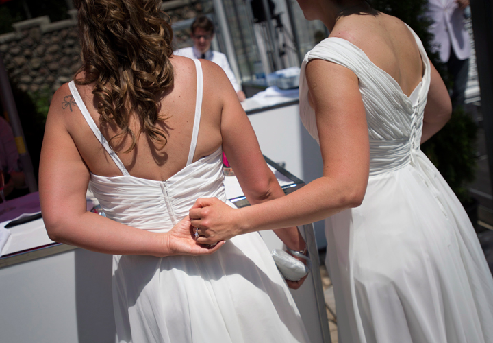 A married couple hold hands after joining over 100 gay couples in a mass wedding during World Pride 2014 at Casa Loma in Toronto, on Thursday, June 26, 2014.