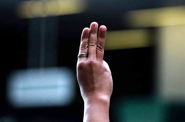 A protester flashes three fingers, representing liberty, brotherhood and equality, during an anti-coup demonstration at a shopping mall in Bangkok, Thailand Sunday, June 1, 2014. 