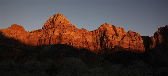FILE - This Jan. 20, 2011 file photo shows shadows creeping up on sandstone cliffs glowing red as the sun sets on Zion National Park near Springdale, Utah. The National Park Service is taking steps to ban drones from 84 million acres of public lands and waterways, saying the unmanned aircraft annoy visitors, harass wildlife.
