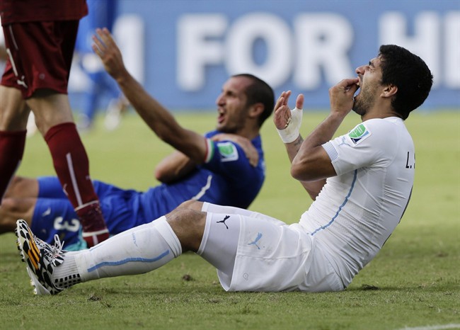  In this June 24, 2014 file photo, Uruguay's Luis Suarez holds his teeth after biting Italy's Giorgio Chiellini's shoulder during the group D World Cup soccer match between Italy and Uruguay at the Arena das Dunas in Natal, Brazil. On Thursday, June 26, 2014, FIFA banned Suarez for 9 games and 4 months for biting his opponent at the World Cup. (AP Photo/Ricardo Mazalan, File).