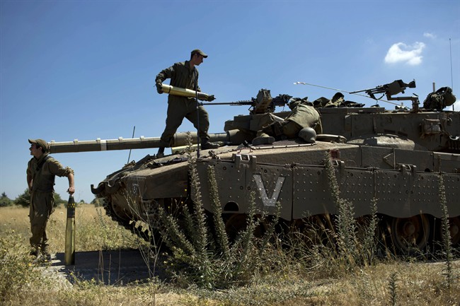 Israeli soldiers load shells in their tank following the first death on the Israeli side of the Golan since the Syrian civil war erupted more than three years ago, near the Israeli village of Alonei Habashan, in the area of Tel Hazeka, close to the Quneitra border crossing in the Israeli-controlled Golan Heights, Sunday, June 22, 2014. 