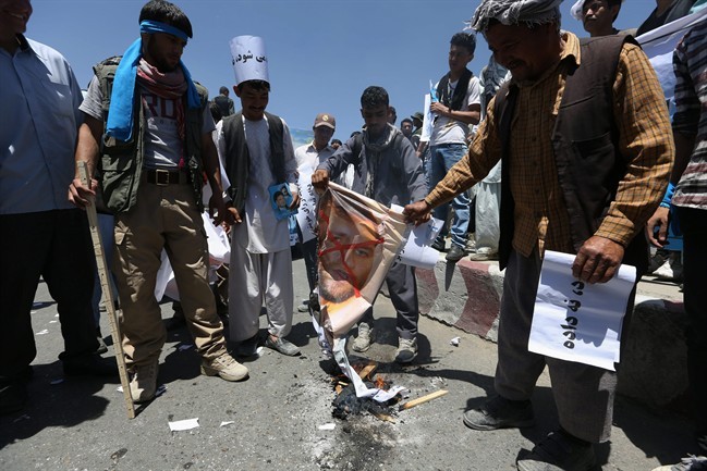 Supporters of presidential candidate Abdullah Abdullah burn a picture of Afghanistan's Independent Election Commission director Ziaulhaq Amarkhil during a protest in Kabul, Afghanistan, Saturday, June 21, 2014. Former Foreign Minister Abdullah, who is running against Ashraf Ghani Ahmadzai, a former finance minister, has accused electoral officials and others of trying to rig the June 14 vote against him. 