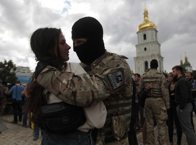 A girl says goodbye to her friend, a volunteer, before they are sent to the eastern part of Ukraine to join the ranks of special battalion "Azov", during a ceremony to take the oath of allegiance to Ukraine, in Kiev, Ukraine, Monday, June 23, 2014.