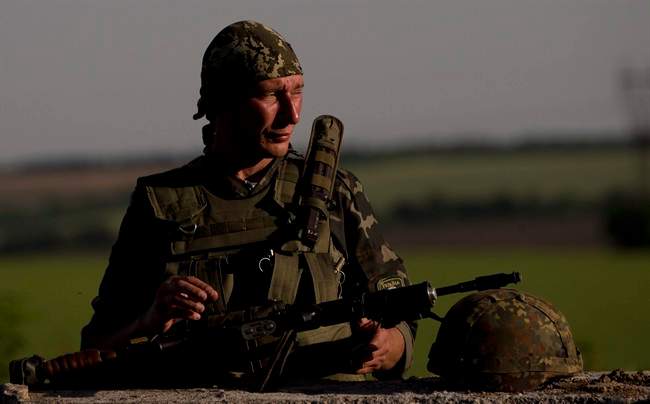 An Ukrainian soldier observes the road at a checkpoint outside the town of Amvrosiivka, eastern Ukraine, close to the Russian border, Thursday, June 5, 2014. 
