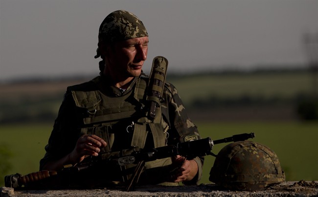 An Ukrainian soldier observes the road at a checkpoint outside the town of Amvrosiivka, eastern Ukraine, close to the Russian border, Thursday, June 5, 2014. 