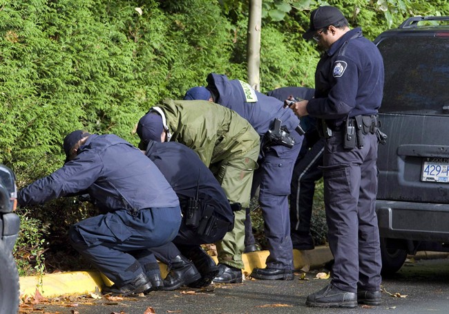 RCMP officers search the property surrounding an apartment building where six people died in a mulitple homicide in Surrey, B.C. Wednesday, Oct. 24, 2007.
