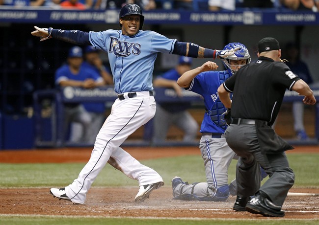 Tampa Bay Rays' Yunel Escobar motions he is safe after sliding into home against Toronto Blue Jays catcher Josh Thole as umpire Sean Barber begins to call him out during the sixth inning of a baseball game Sunday, July 13, 2014, in St. Petersburg, Fla.