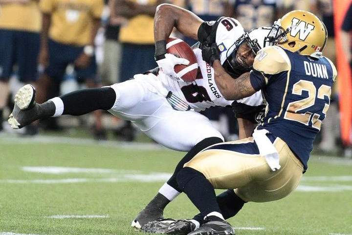 Marcus Henry of the Ottawa RedBlacks is tackled by Desia Dunn of the Winnipeg Blue Bombers at Investors Group Field on Thursday in Winnipeg.