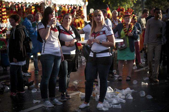 Fans drink beer in front of a beer stand at the Hyundai Fan Park public viewing area named ‘Fan Mile’ in front of the Brandenburg Gate in Tiergarten park after watching the FIFA World Cup 2014 group G football match Germany vs USA on a giant screen on June 26, 2014 in Berlin, Germany.