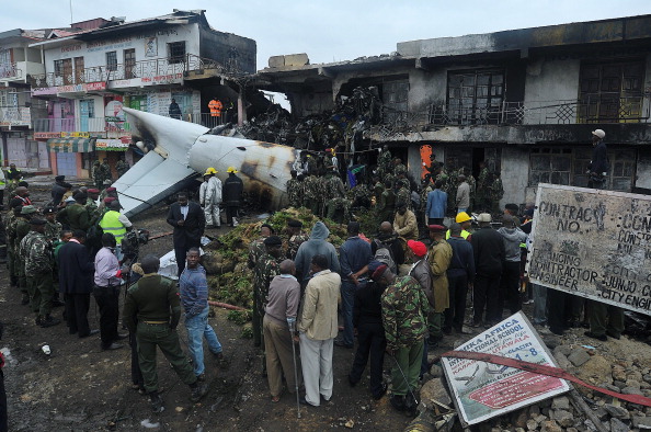 Rescuers and onlookers look at the wreckage of a cargo plane which crashed at a commercial building in a Nairobi susburb shortly after takeoff on July, 2, 2014  from the Kenyan capital's main airport, the busiest in east African. The Fokker 50 cargo airplane crashed with four crew just outside the airport as it took off to ferry khat to neighbouring Somalia. 