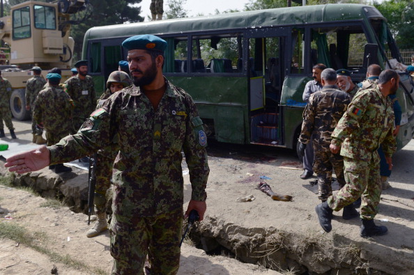 Afghan National Army (ANA) soldiers stand next to the wreckage of a military bus at the site of a suicide attack in Kabul on July 2,2014.
