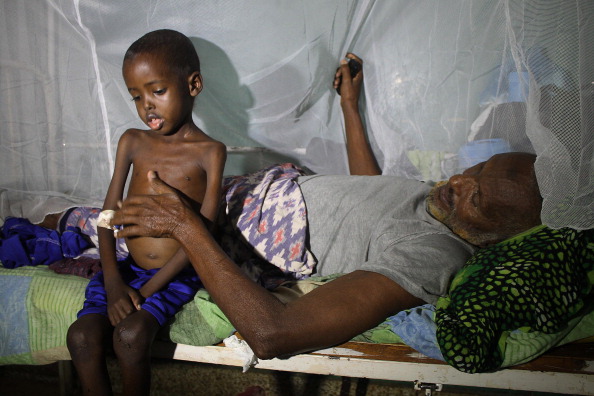 A patient lies on a bed on July 15, 2015 next to a malnourished child at Banadir hospital in Mogadishu. 