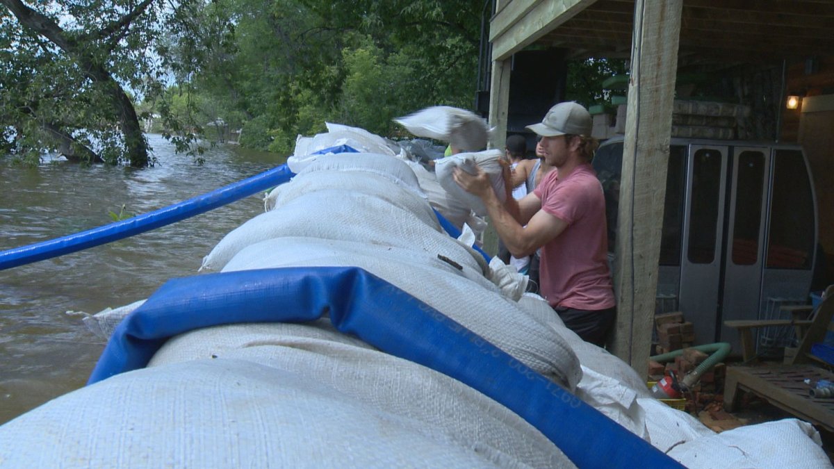 Blaine Hill adds more sandbags to the barricade on Sunday in Bird's Point, Sask.