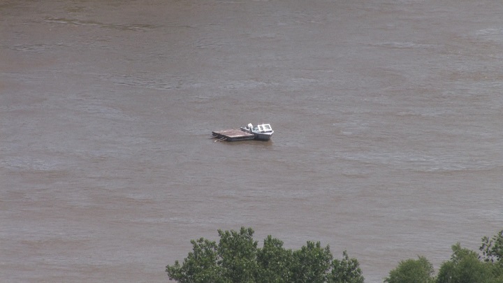 A boat and the dock it was attached to drifted down the Red River in Winnipeg on Friday, July 11, 2014.