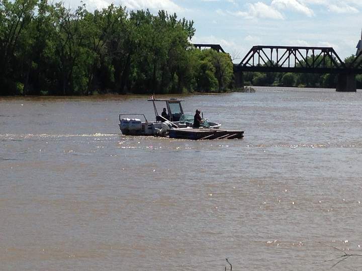 Police river patrol boat takes control of drifting boat and dock on the Red River in Winnipeg on Friday, July 11, 2014