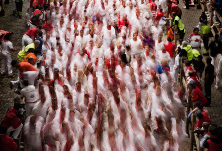 In this slow shutter speed photo, revelers run after Torrestrella’s ranch fighting bulls during the running of the bulls of the San Fermin festival, in Pamplona, Spain, Monday, July 7, 2014.