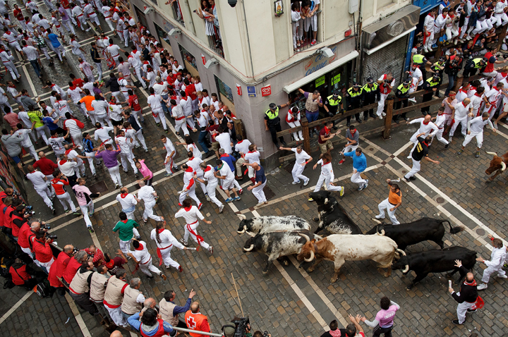 Revellers run with Torrestrella’s fighting bulls along the Curva de Estafeta during the second day of the San Fermin Running Of The Bulls festival on July 7, 2014 in Pamplona, Spain.