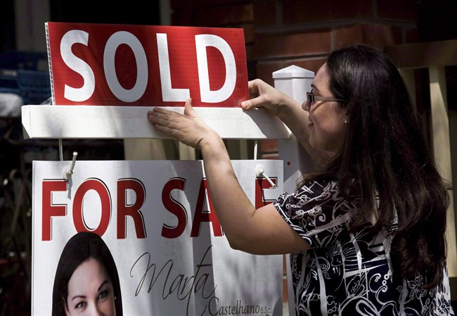 A real estate agent puts up a "sold" sign in front of a house in Toronto April 20, 2010. THE CANADIAN PRESS/Darren Calabrese.