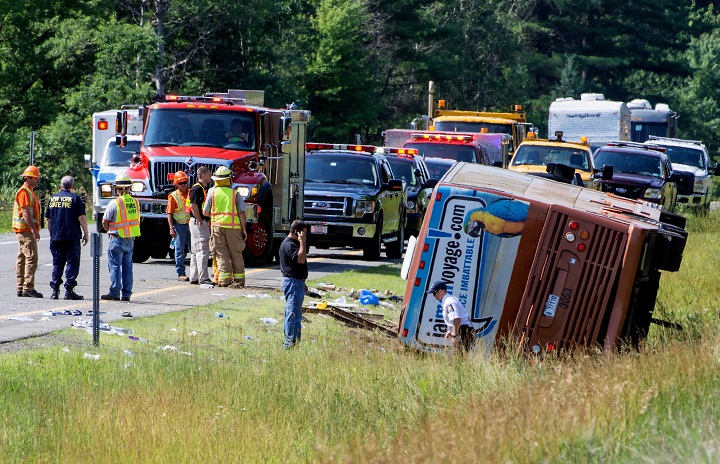 Investigators look over the scene of a bus accident on Interstate 87, also known as the Adirondack Northway, in North Hudson, N.Y. on Friday July 18, 2014.