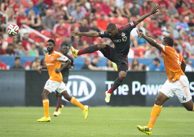 Toronto FC's Jermain Defoe, centre, leaps for a ball during the first half of MLS soccer action against the Houston Dynamos in Toronto on Saturday, July 12, 2014. THE CANADIAN PRESS/Darren Calabrese.