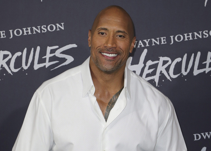 Dwayne "The Rock" Johnson poses for photos as he arrives on the red carpet for the premiere of his latest movie Hercules in Sydney, Australia, Thursday, June 19, 2014. 
