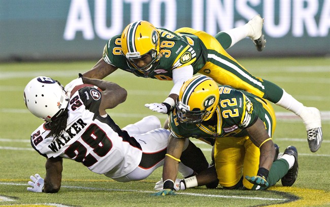 Ottawa RedBlacks' Chevon Walker (29) is tackled by Edmonton Eskimos' Eric Samuels (38) and Joe Burnett (22) during second half action in Edmonton, Alta., on Friday July 11, 2014.