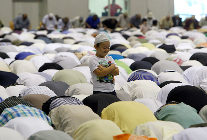 A young boy stands as Muslims pray during the Eid al Fitr prayer marking the end of the Islam’s holy fasting month of Ramadan at the Exhibition Center of the Parc Chanot, in Marseille, southern France, Monday, July 28, 2014.
