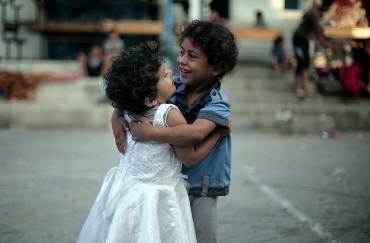 Two Palestinian girls dance while celebrating the First day of Eid al-Fitr in a United Nations school where dozens of families have sought refuge after fleeing their home in fear of Israeli airstrikes, in Jabaliya refugee camp, northern Gaza Strip, Monday, July 28, 2014.