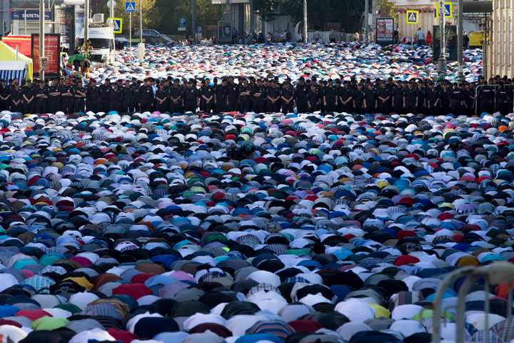 Muslim men, bowing toward Mecca, offer Eid al-Fitr prayers that marks the end of the holy fasting month of Ramadan as police guard them at the main mosque in Moscow, Russia, Monday, July 28, 2014. More than two hundred thousand Muslims gathered at Moscow's mosques to celebrate the Eid al-Fitr.