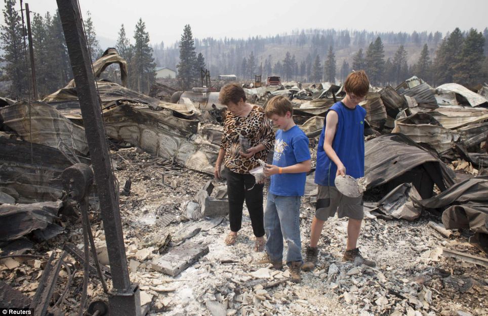 Mim Morris (L) and her grandsons look through the remnants of her home, which was destroyed by the Carlton Complex Fire. 