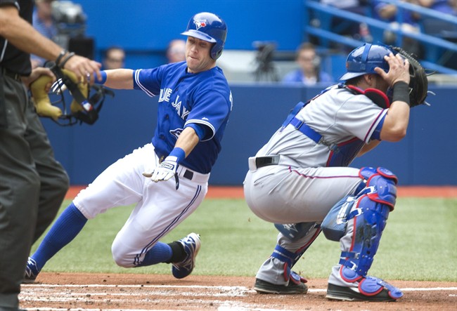 Toronto Blue Jays Steve Tolleson goes around Texas Rangers' catcher Geovany Soto to score on a hit by Blue Jays Jose Reyes during second inning of baseball game in Toronto on Sunday, July 20, 2014. (AP Photo/The Canadian Press, Fred Thornhill).