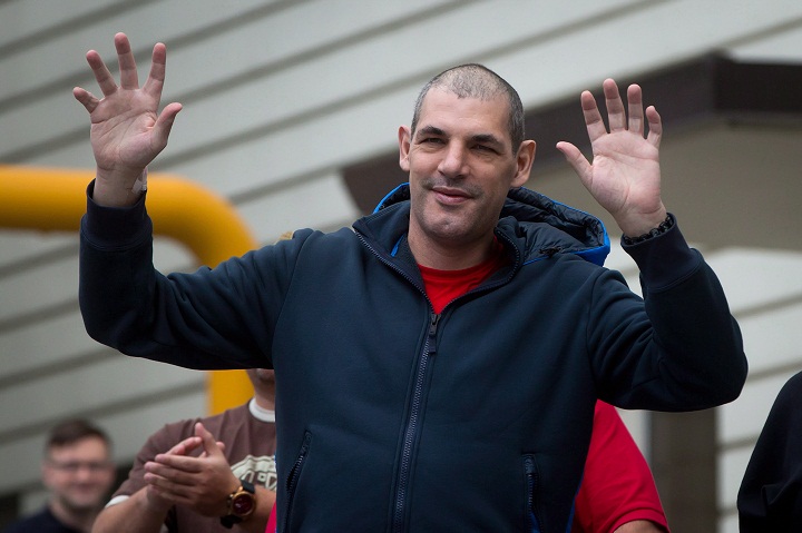 Former Vancouver Canucks' enforcer Gino Odjick gets up out of a wheelchair and waves to hundreds of fans that gathered to support him outside Vancouver General Hospital in Vancouver, B.C., on Sunday June 29, 2014.